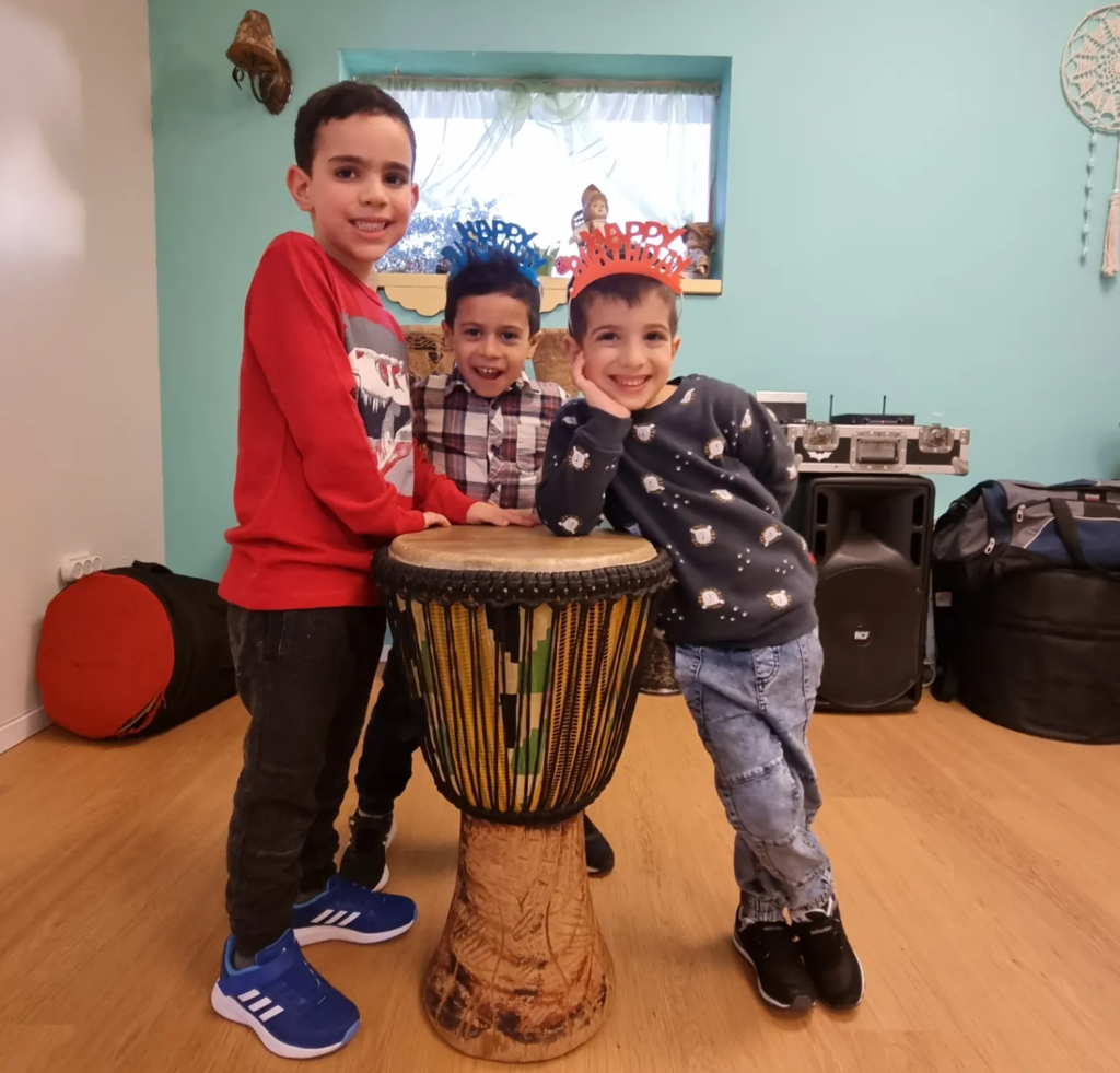מעגל מתופפים לילדים מחיר אטרקטיבי בבובינגה- 3 ילדים מחייכים ומתופפים על תוף גדול